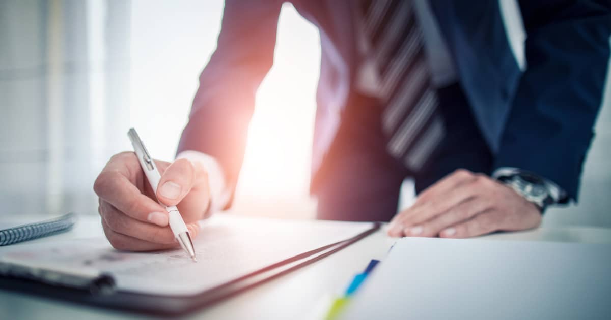 Business man signing contract document on office desk, making a deal.