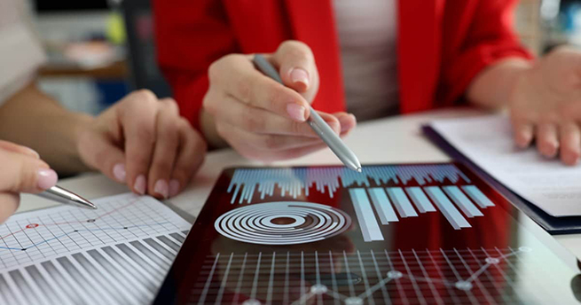 Business women studying charts and diagrams on digital tablet closeup